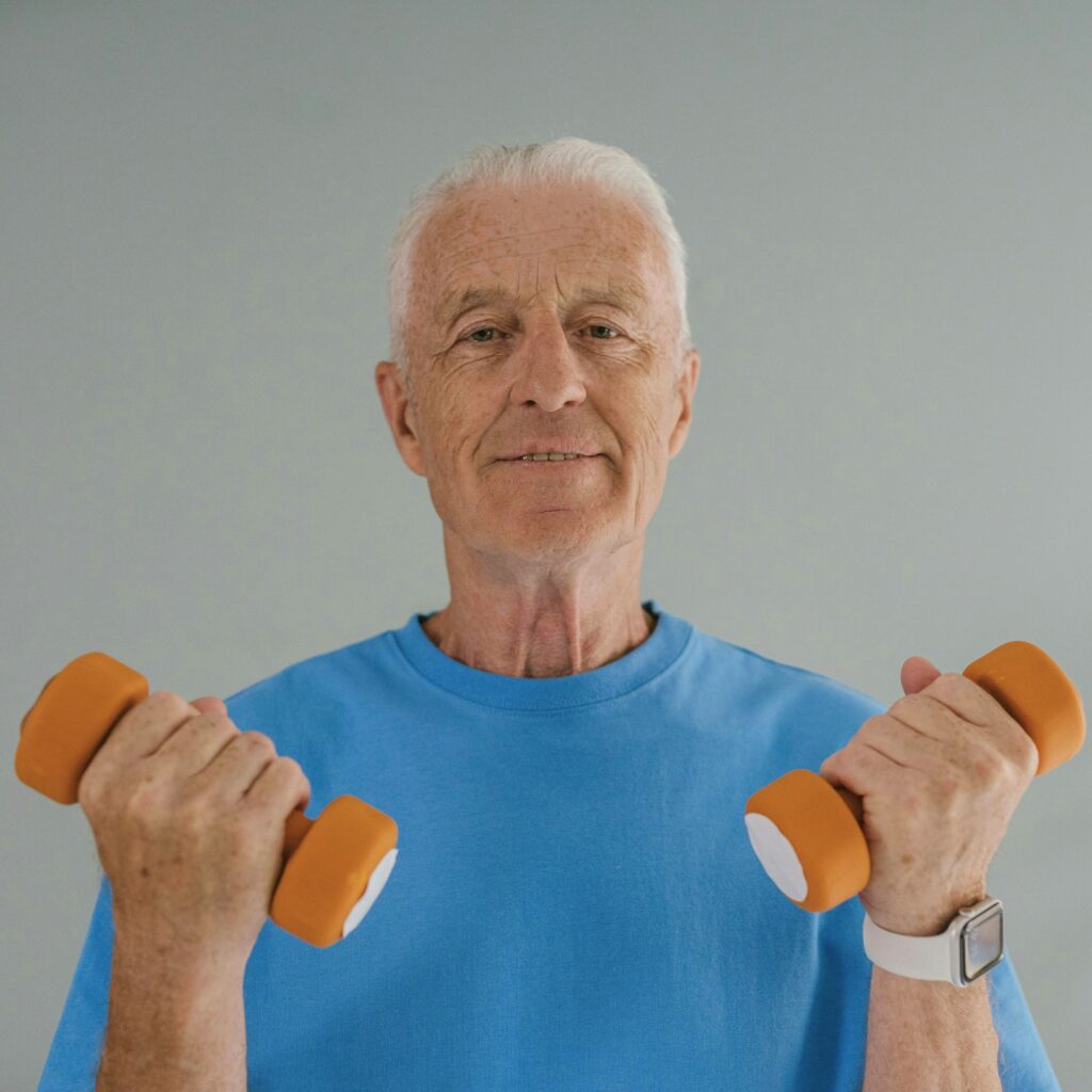 Elderly man lifting small weights to demonstrate the importance of strength training.